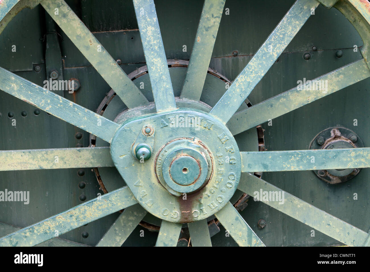 Vecchio, antichi ruota di carro con weathered legno e metallo arrugginito parti in un campo erboso. Chiudere la gamma. Foto Stock