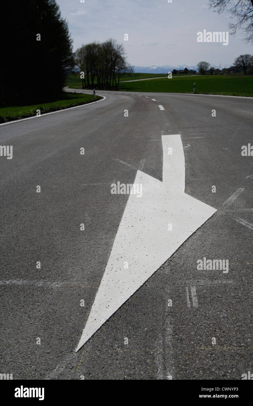 In Germania, in Baviera, la vista di freccia bianca segno marcatura su strada Foto Stock