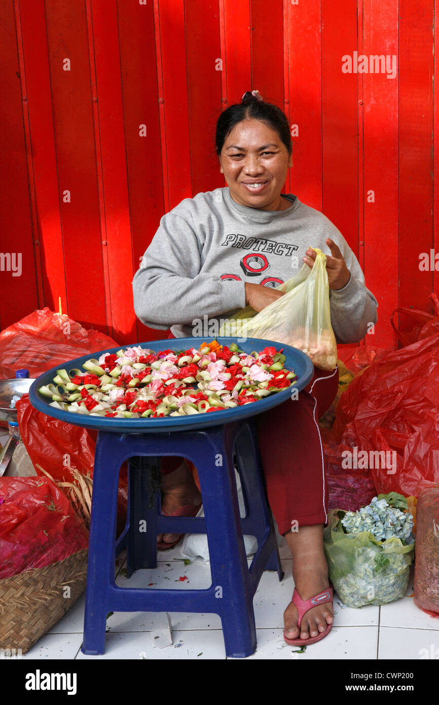 Un sorridente donna balinese facendo offerte che sono utilizzati come parte della religione indù. Mercati di Ubud, Bali, Indonesia Foto Stock