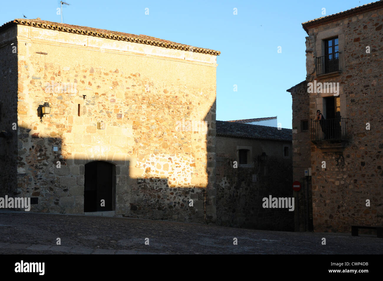 Una donna si appoggia sul balcone in Caceres città vecchia. Foto Stock