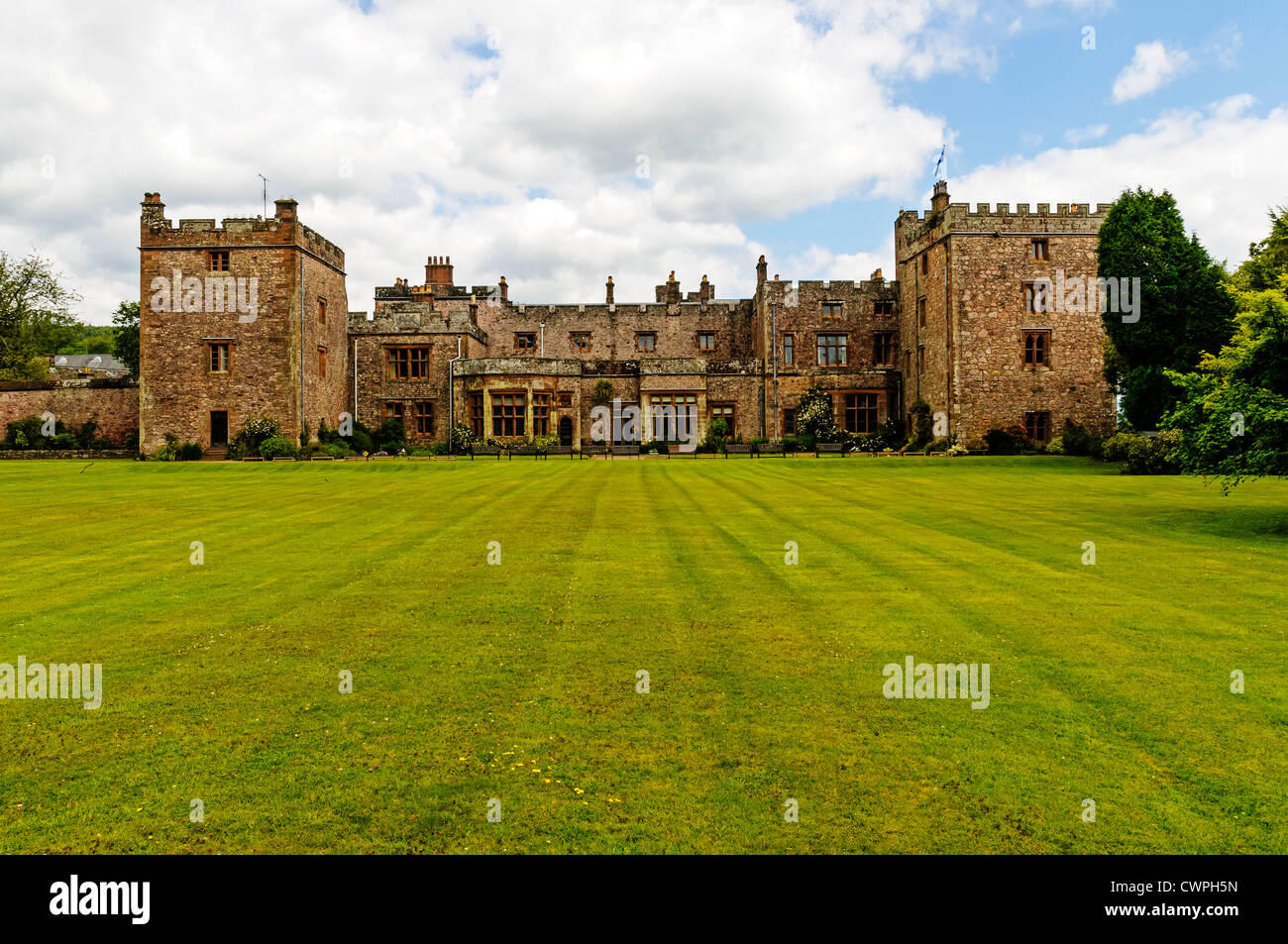 La storica facciata medievale di Muncaster Castle con le sue due torri merlate come si vede dal fondo del prato Foto Stock