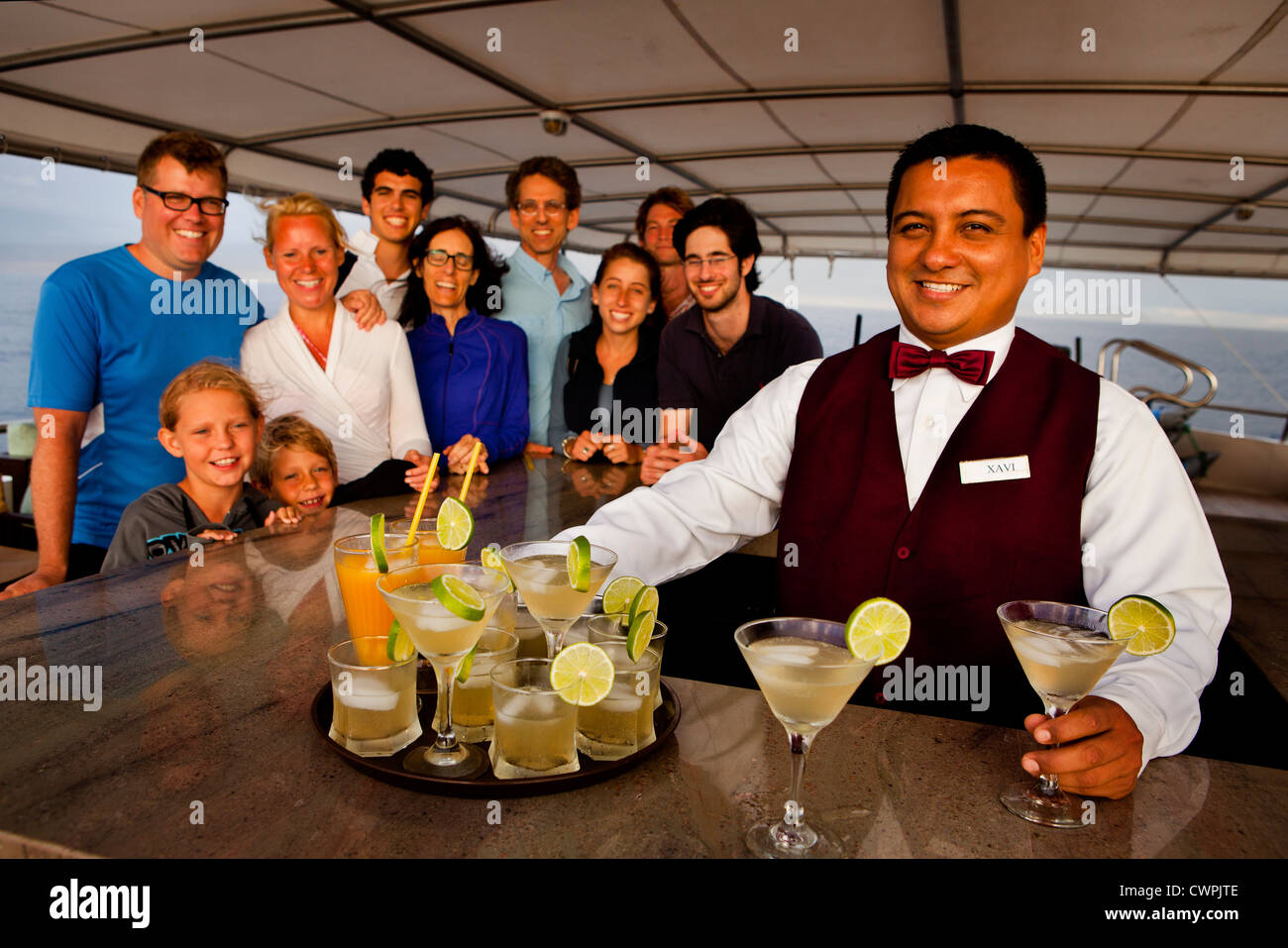 Ora del Cocktail a bordo della Grand Odyssey con Xavi, il barman, di servire gli ospiti al tramonto, Isole Galapagos, Ecuador Foto Stock