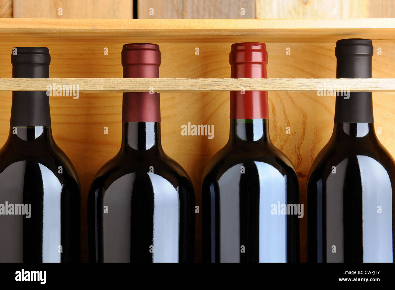 Primo piano di quattro bottiglie di vino rosso in una cassa di legno. Foto Stock