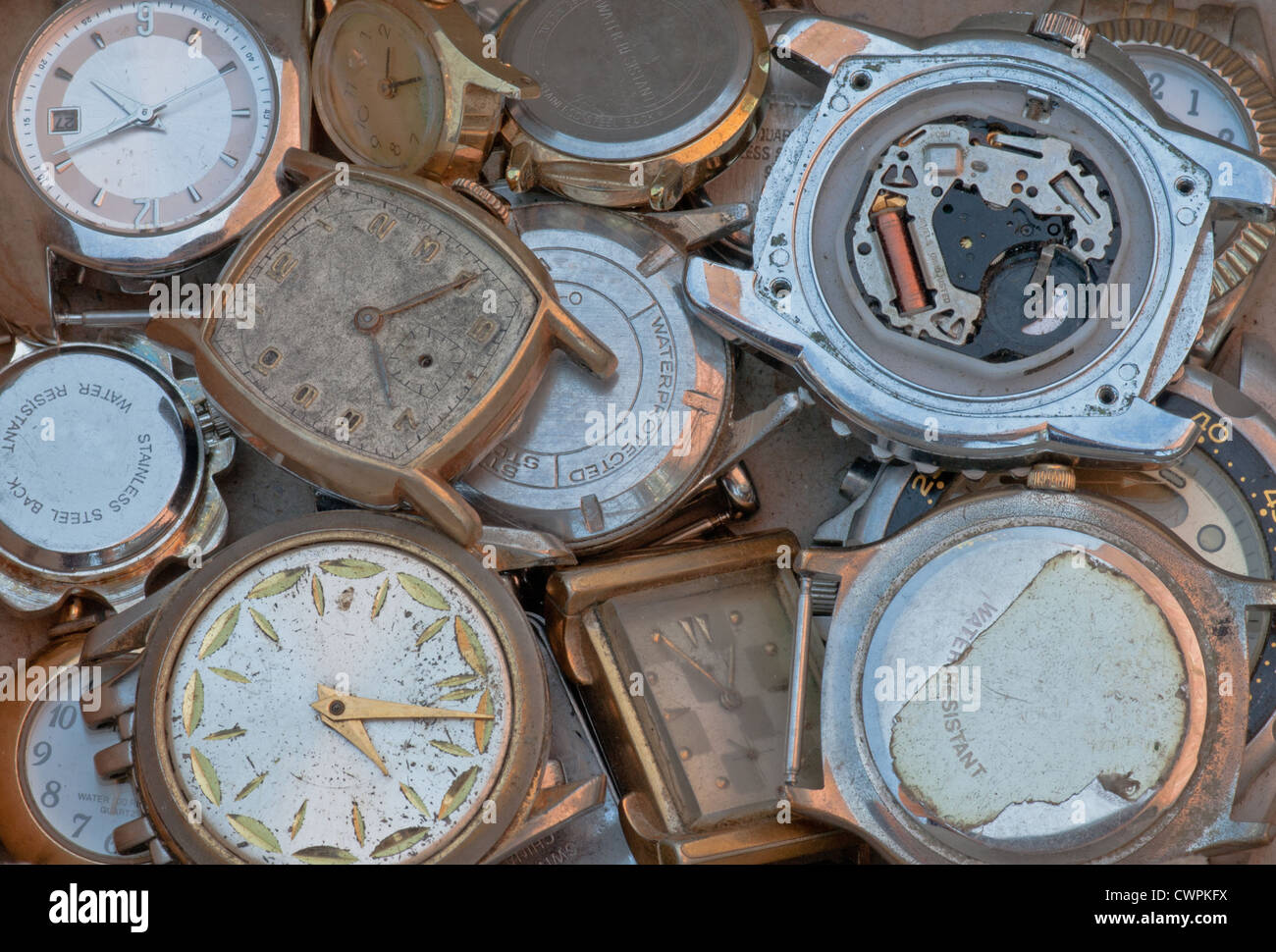Pila di vecchi orologi di metallo scartati facce e parti. Assortimento scarti. Foto Stock