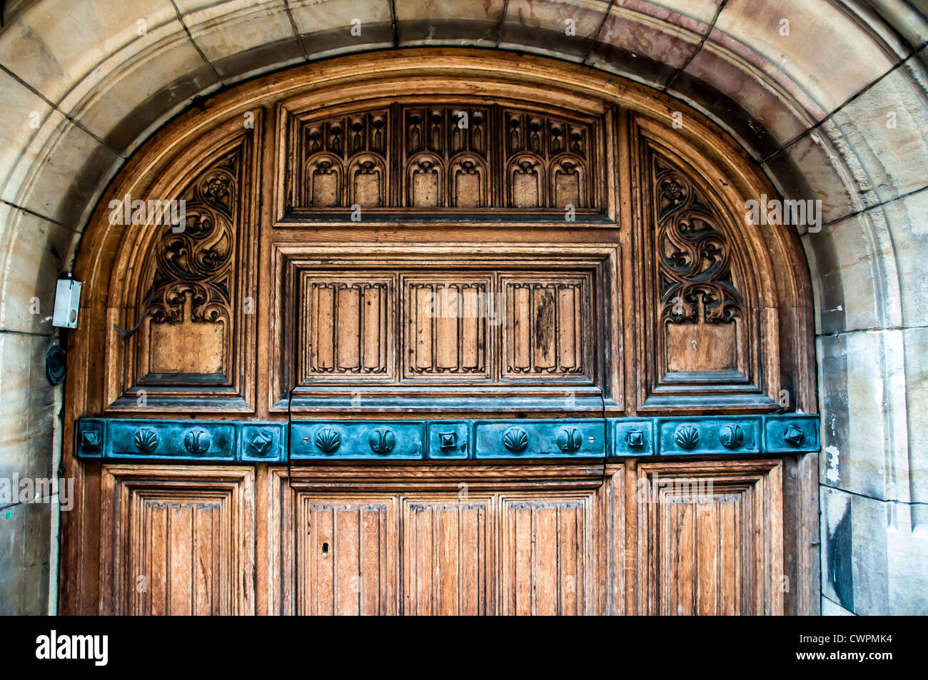 Bella porta di legno con intagli circondato con arco in pietra Foto Stock