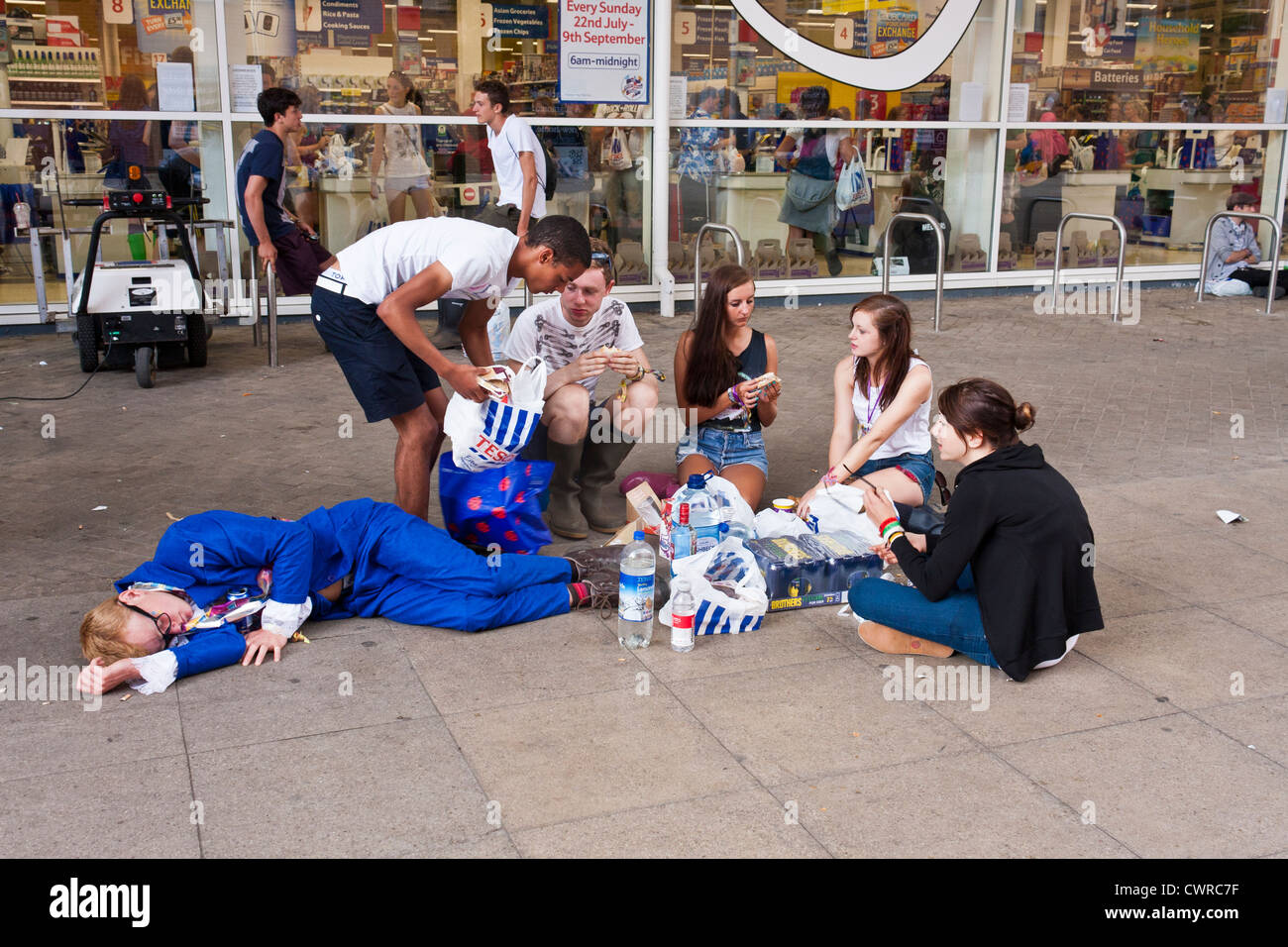 Giovani appassionati di musica al Festival della lettura si prendono una pausa per il pranzo al di fuori di un supermercato locale vicino al festival di musica sito. Foto Stock