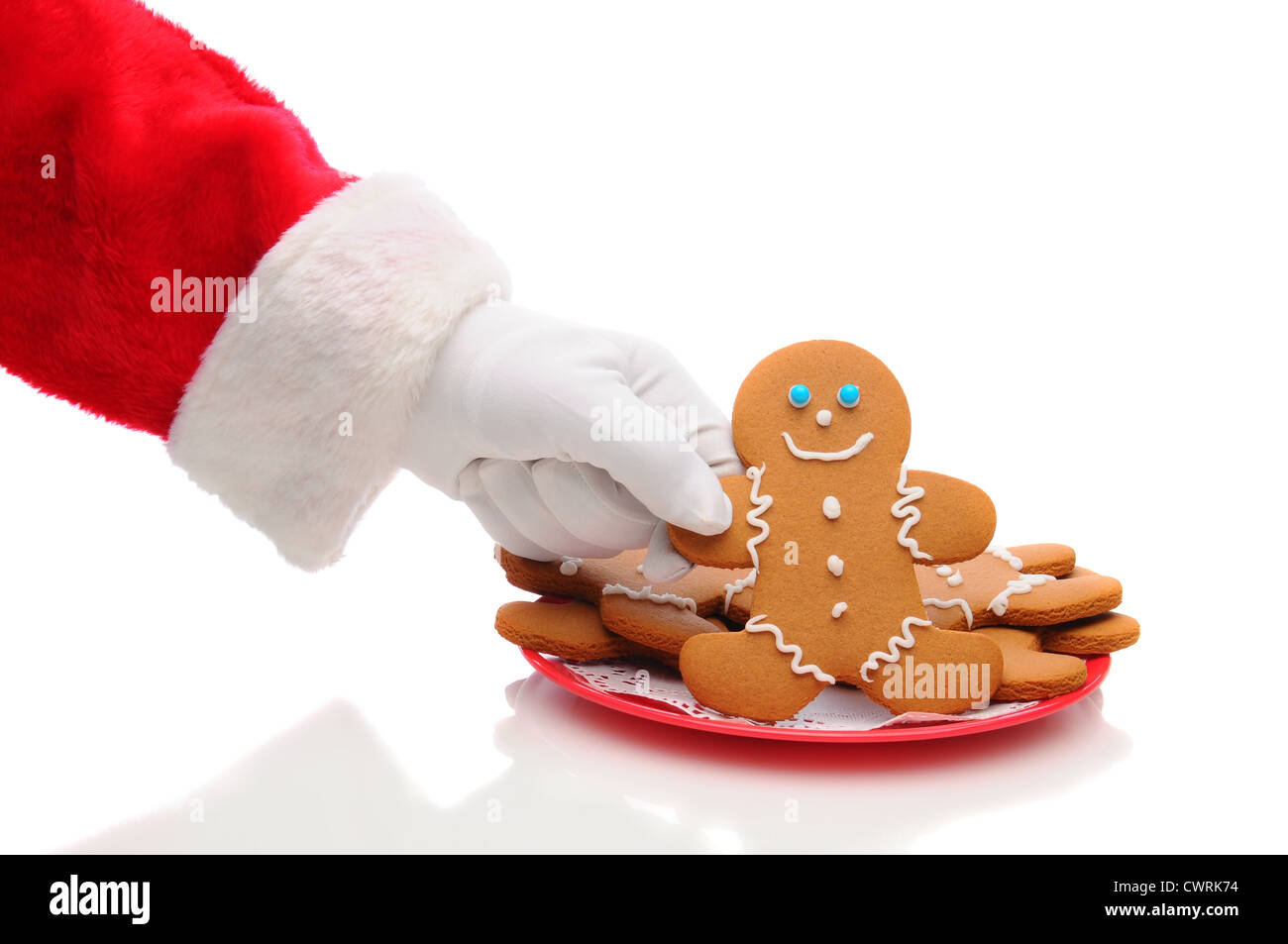 Santa Claus raggiungendo il braccio per prendere un omino di pan di zenzero cookie dalla piastra. Foto Stock