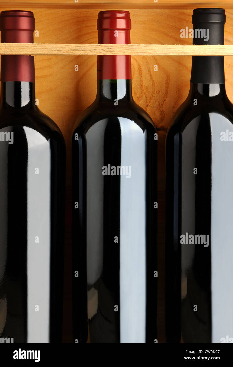 Primo piano di tre bottiglie di vino rosso in una cassa di legno. Formato verticale. Foto Stock