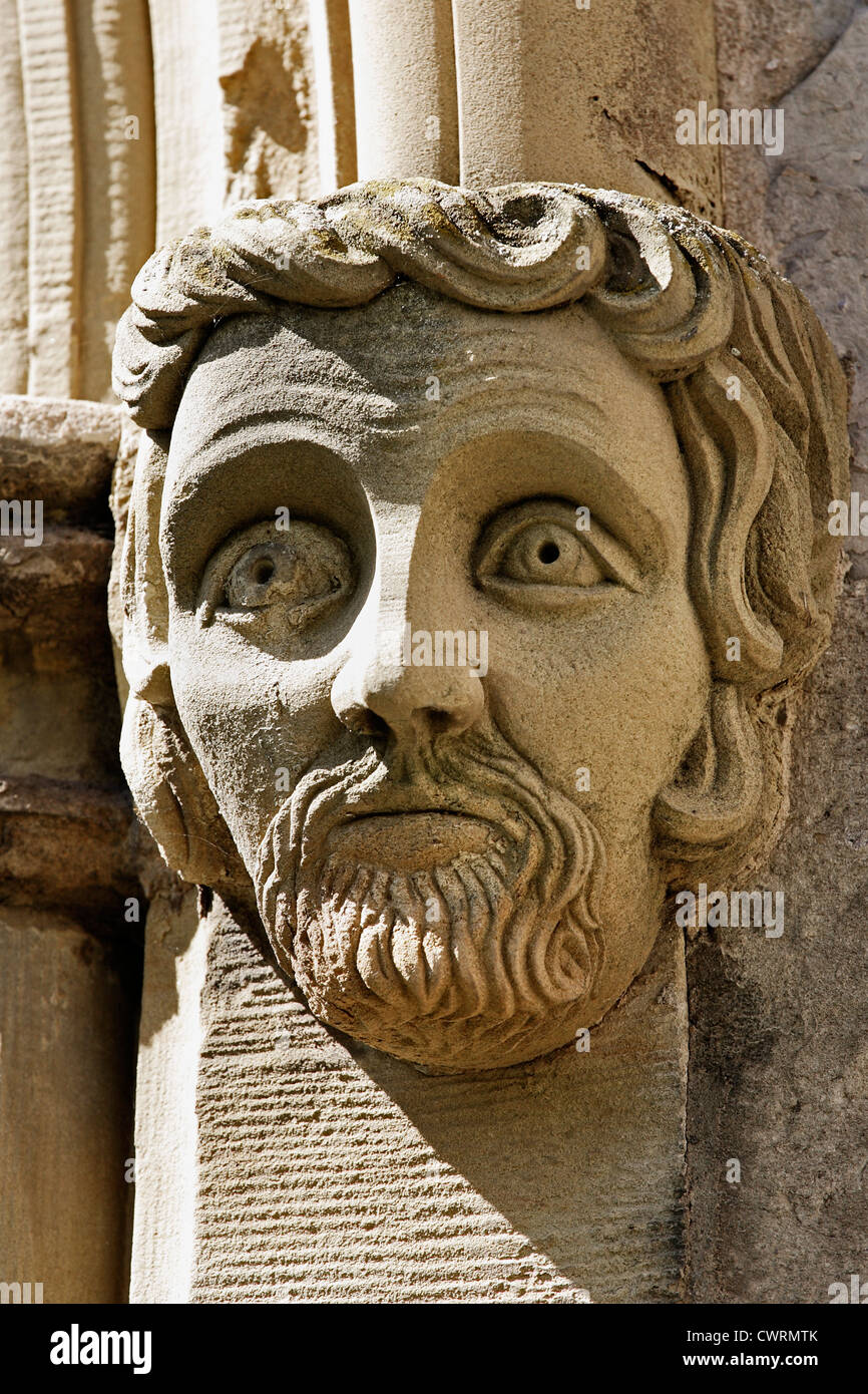 Una testa scolpita sulla parete esterna di una chiesa. Foto Stock