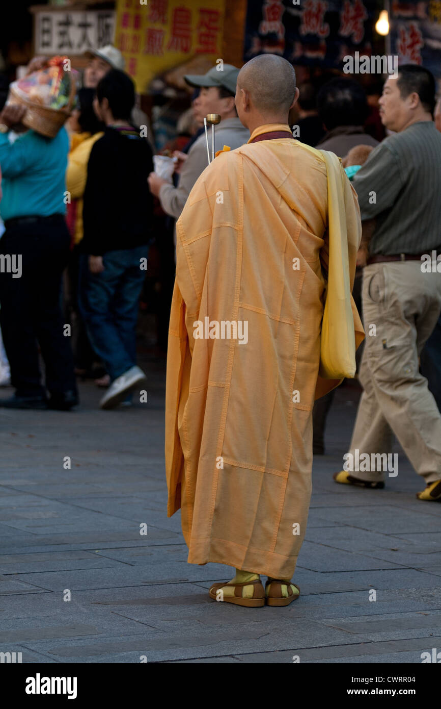 Un monaco buddista sorge su una strada con una folla in retro durante un festival in Sanxia vicino a Taipei, Taiwan Foto Stock