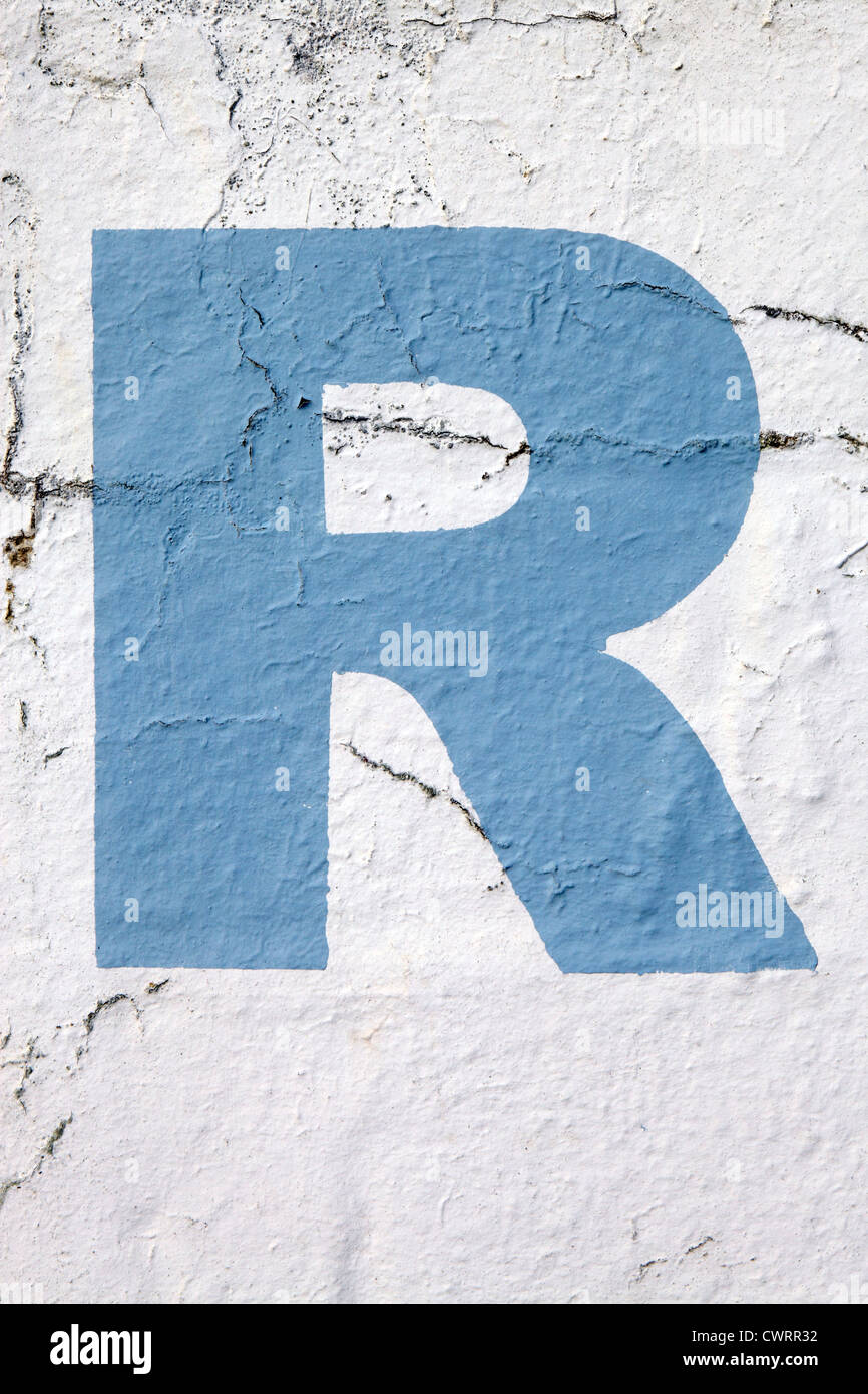 Lettera maiuscola "R" nel cielo della vernice blu stampata su di sbriciolamento di parete esterna, UK. Per le altre lettere vedi Nick Sinclair folio Foto Stock
