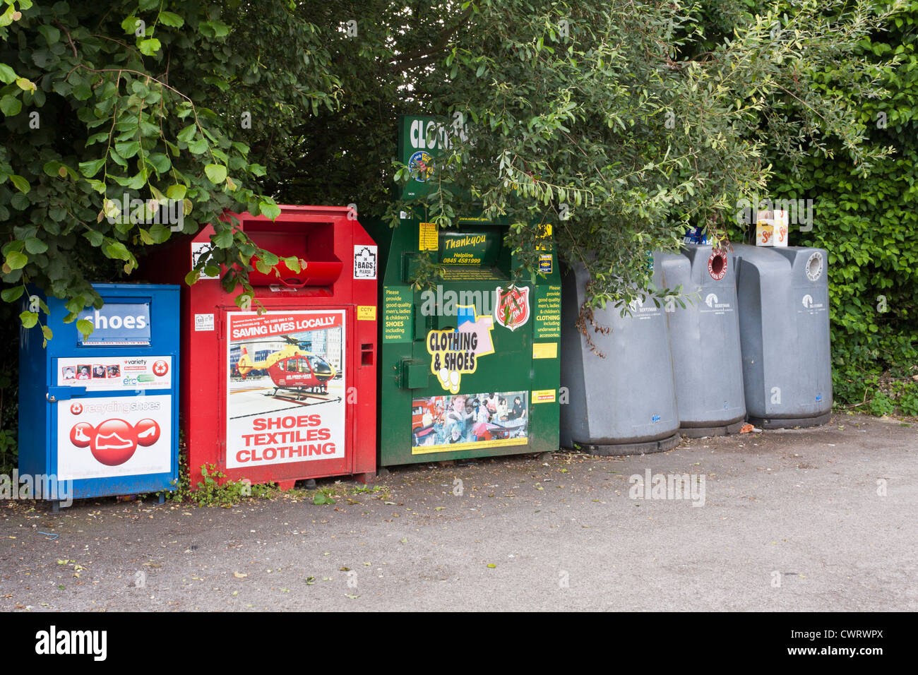 Una linea della carità cassonetti per il riciclaggio del vetro e abbigliamento. Foto Stock