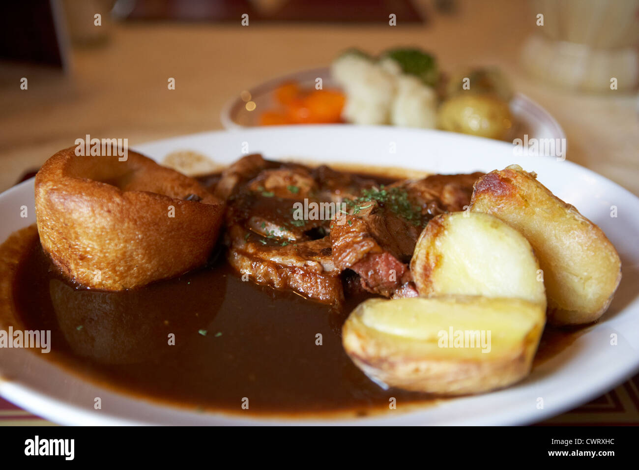 cena di arrostire la domenica servita in un pub con patate arrosto di agnello, verdure di budino dello yorkshire e sugo di scozia, regno unito Foto Stock