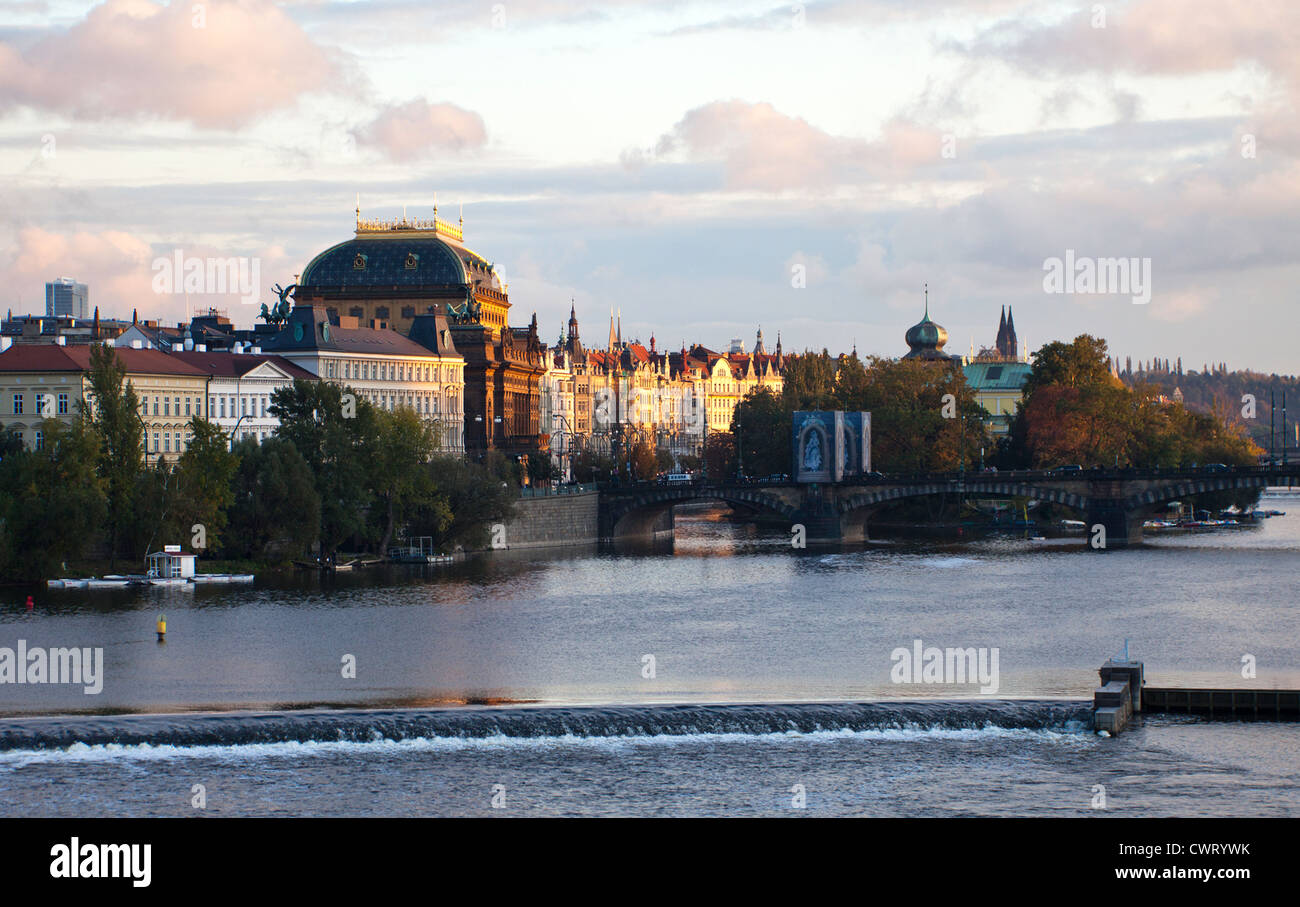 Praga, Repubblica Ceca: il sole del tardo pomeriggio dora nostra il Teatro Nazionale (Narodni Divadlo) sul fiume Moldava. Foto Stock