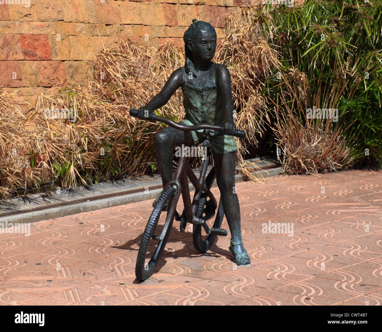 Una scultura in bronzo di una ragazza su una bicicletta. Foto Stock