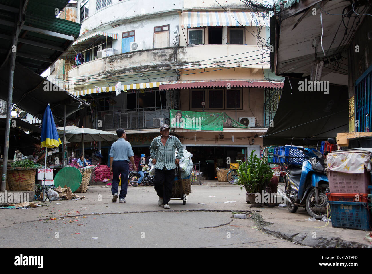 Thai uomo tira un carrello intorno a Pak Klong Talad (mercato dei fiori) a Bangkok, in Thailandia Foto Stock