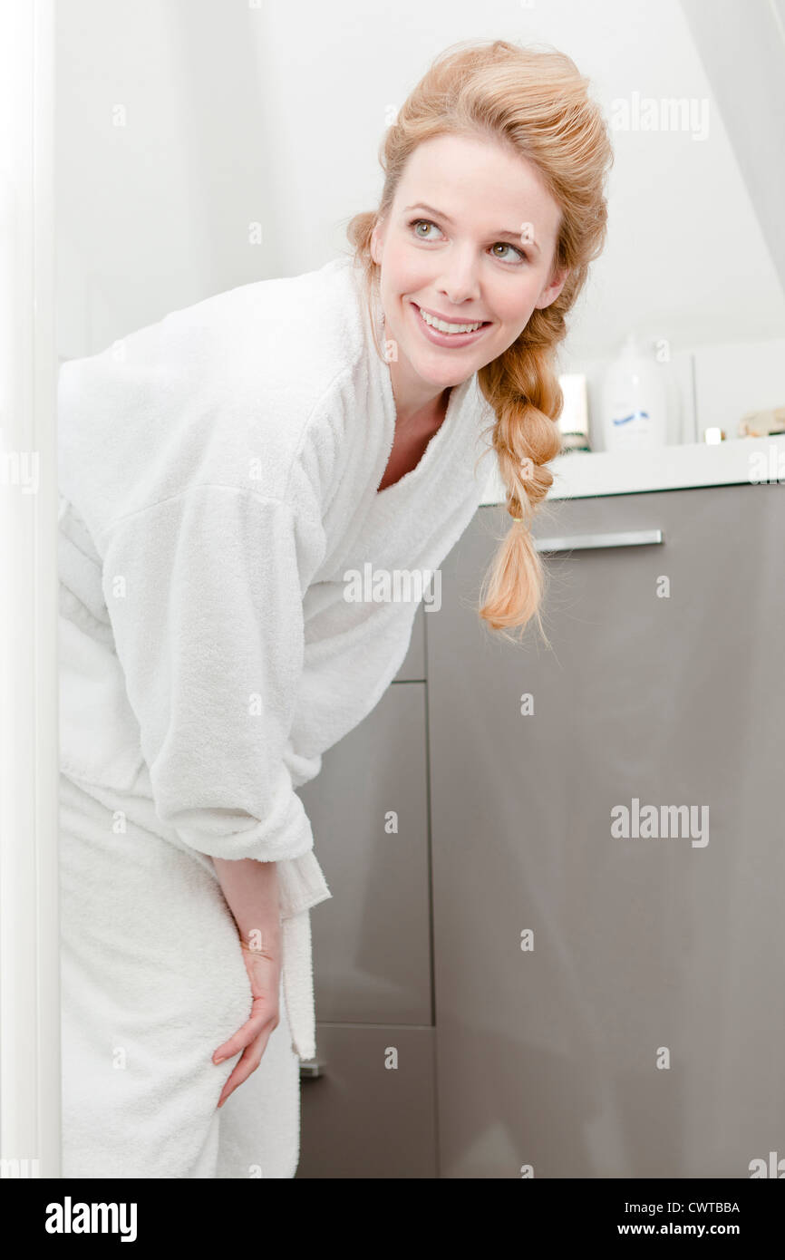 Giovane donna bionda in accappatoio sorridente Foto Stock