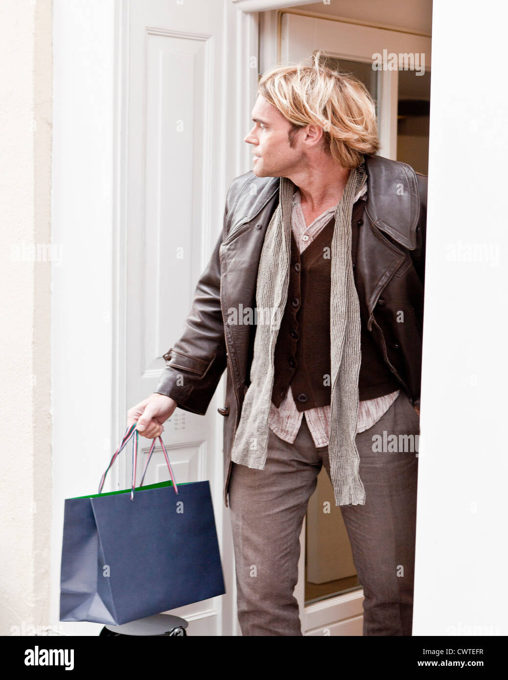 Uomo con shopping bag in piedi nella porta Foto Stock