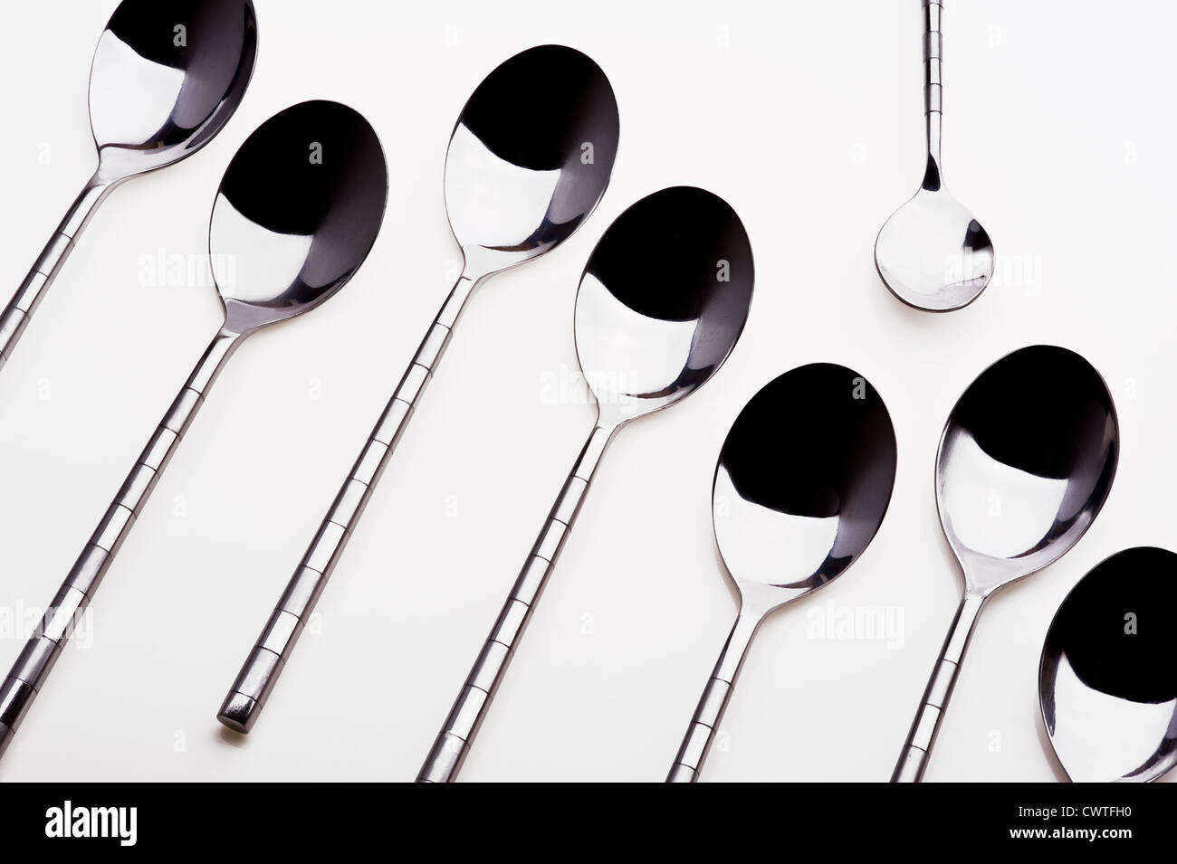 Gruppo di cucchiaini da dessert con un cucchiaino in piedi da solo. Foto Stock