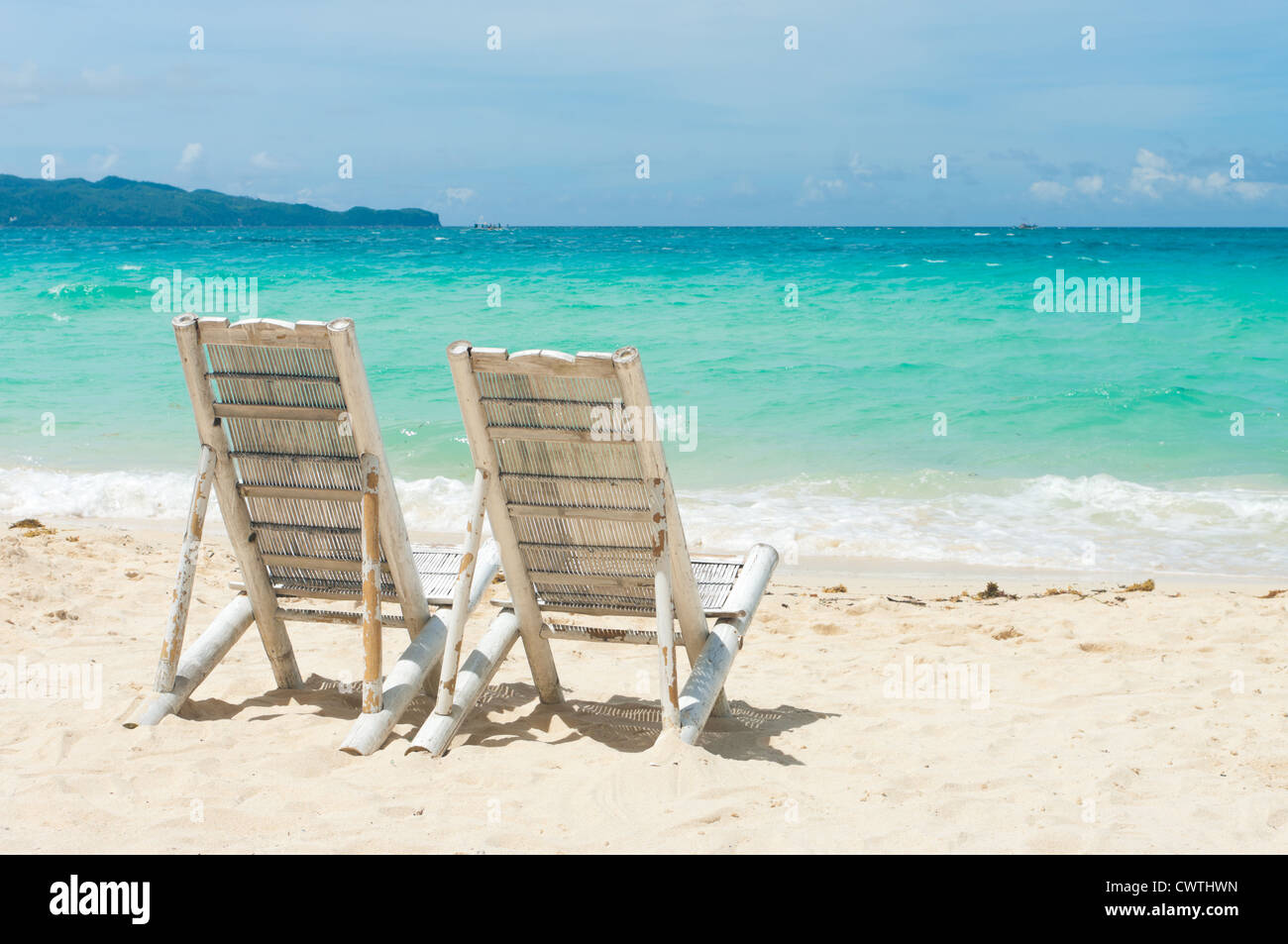 Spiaggia tropicale con due sedie a sdraio di fronte al mare blu Foto stock  - Alamy
