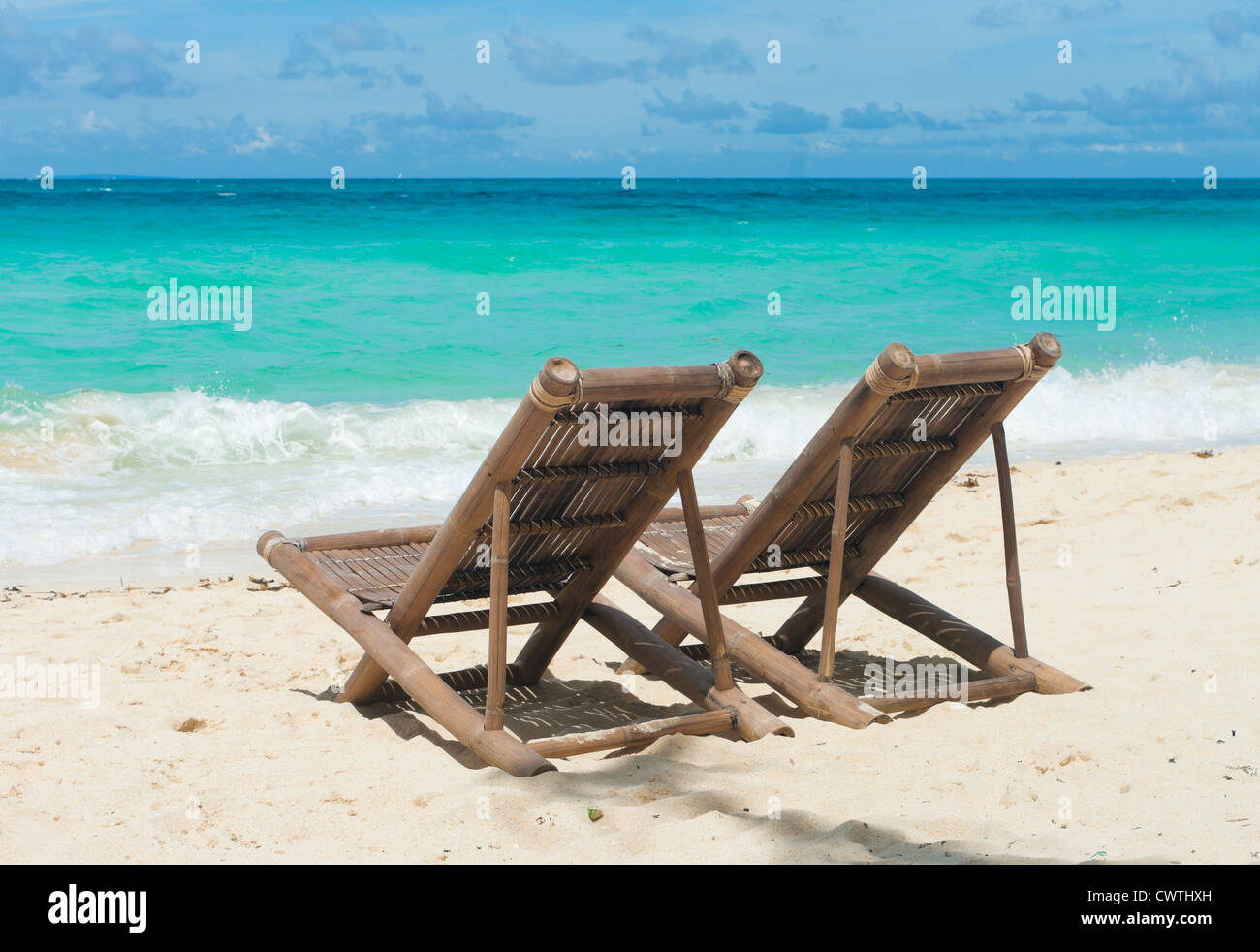 Spiaggia tropicale con due sedie a sdraio di fronte al mare blu Foto Stock