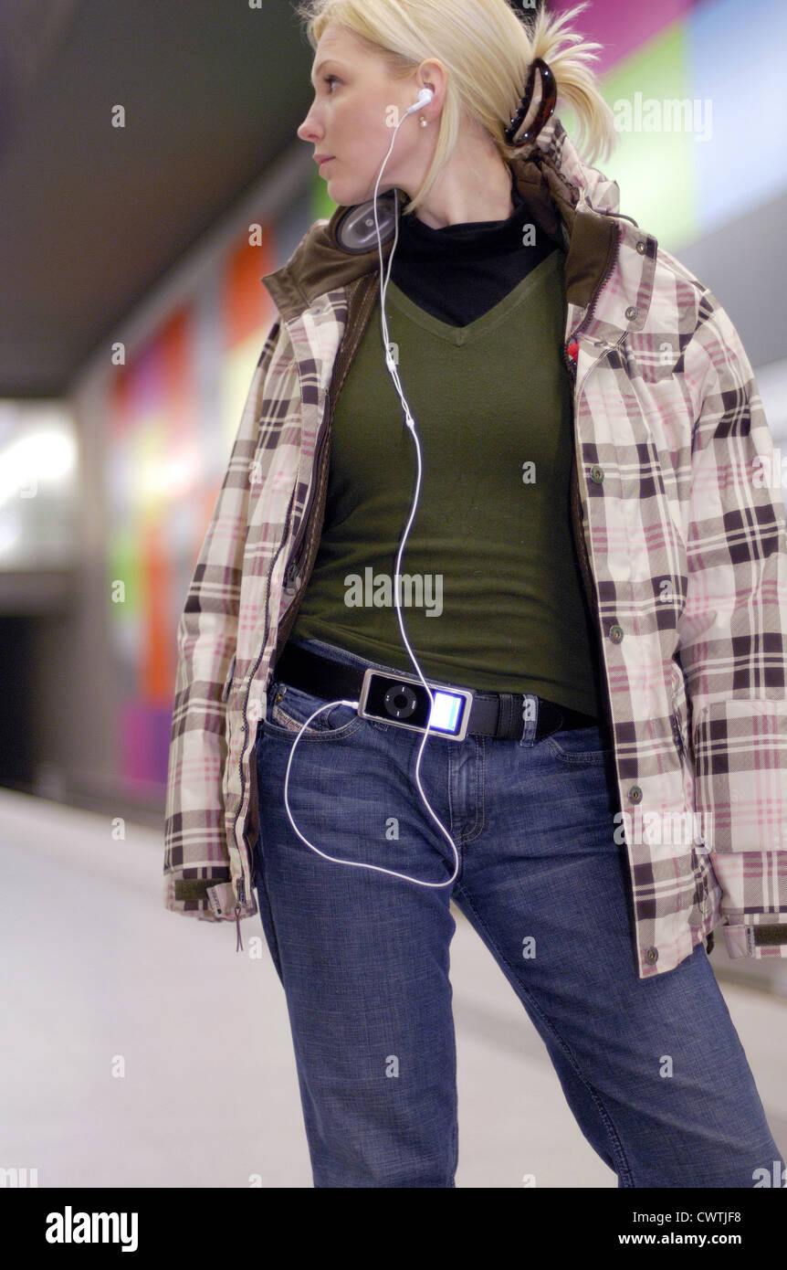 Giovane donna con gli auricolari nella stazione della metropolitana Foto Stock