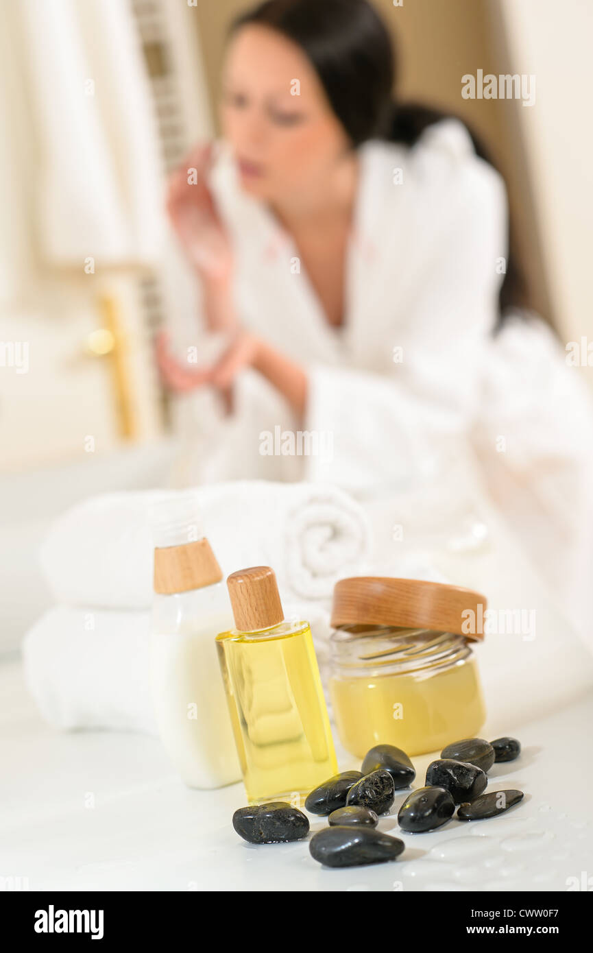 Close-up di prodotti per la cura del corpo in bagno con donna in background Foto Stock