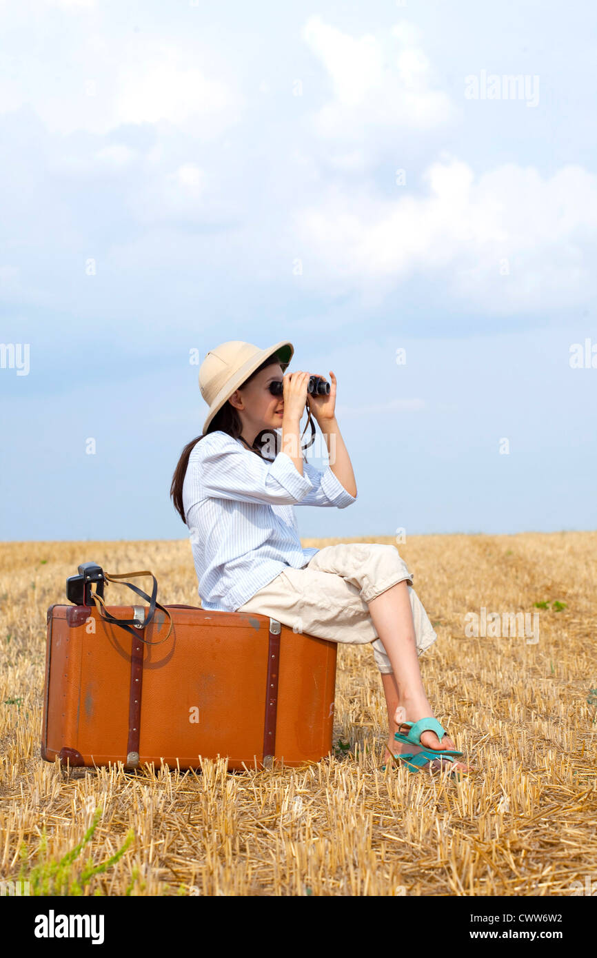 Poco 9 anni che viaggiano ragazza sul campo mietuto con il vecchio valise. Foto Stock