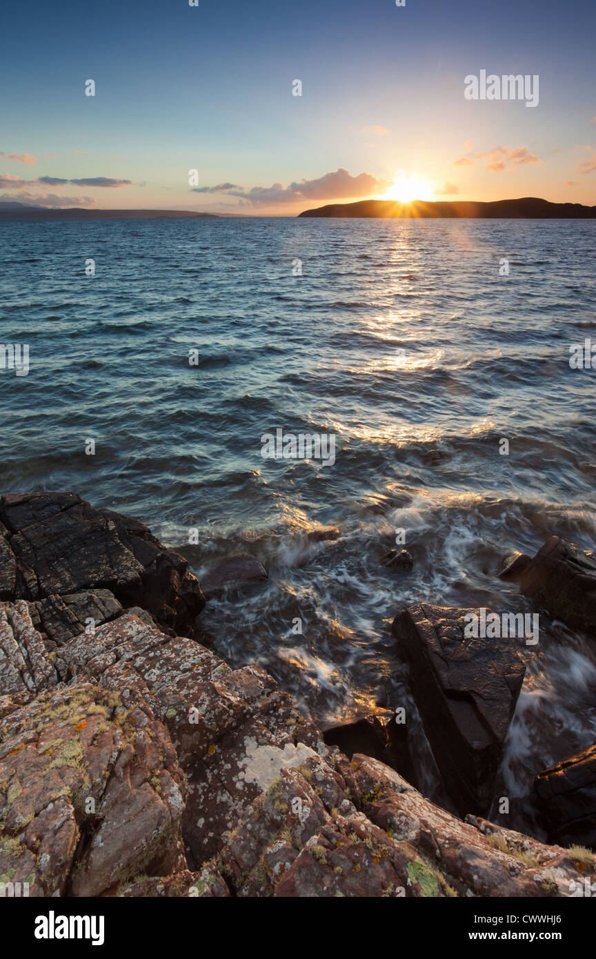 Il sole tramonta dietro il cavallo isola vicino l'estate Isles, North West Highlands della Scozia. Foto Stock