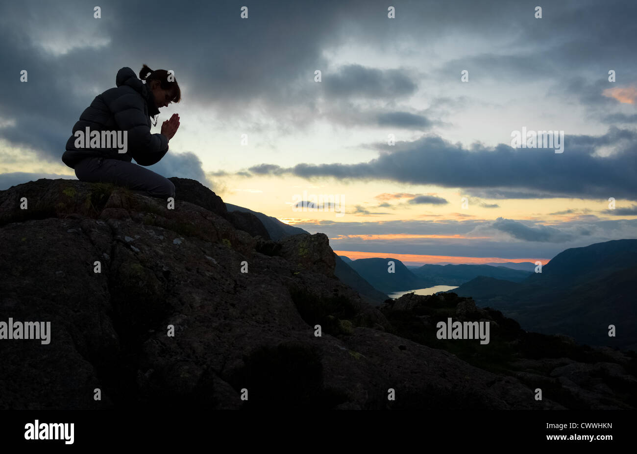 Una donna in preghiera a Dio sulla cima di una montagna. Foto Stock