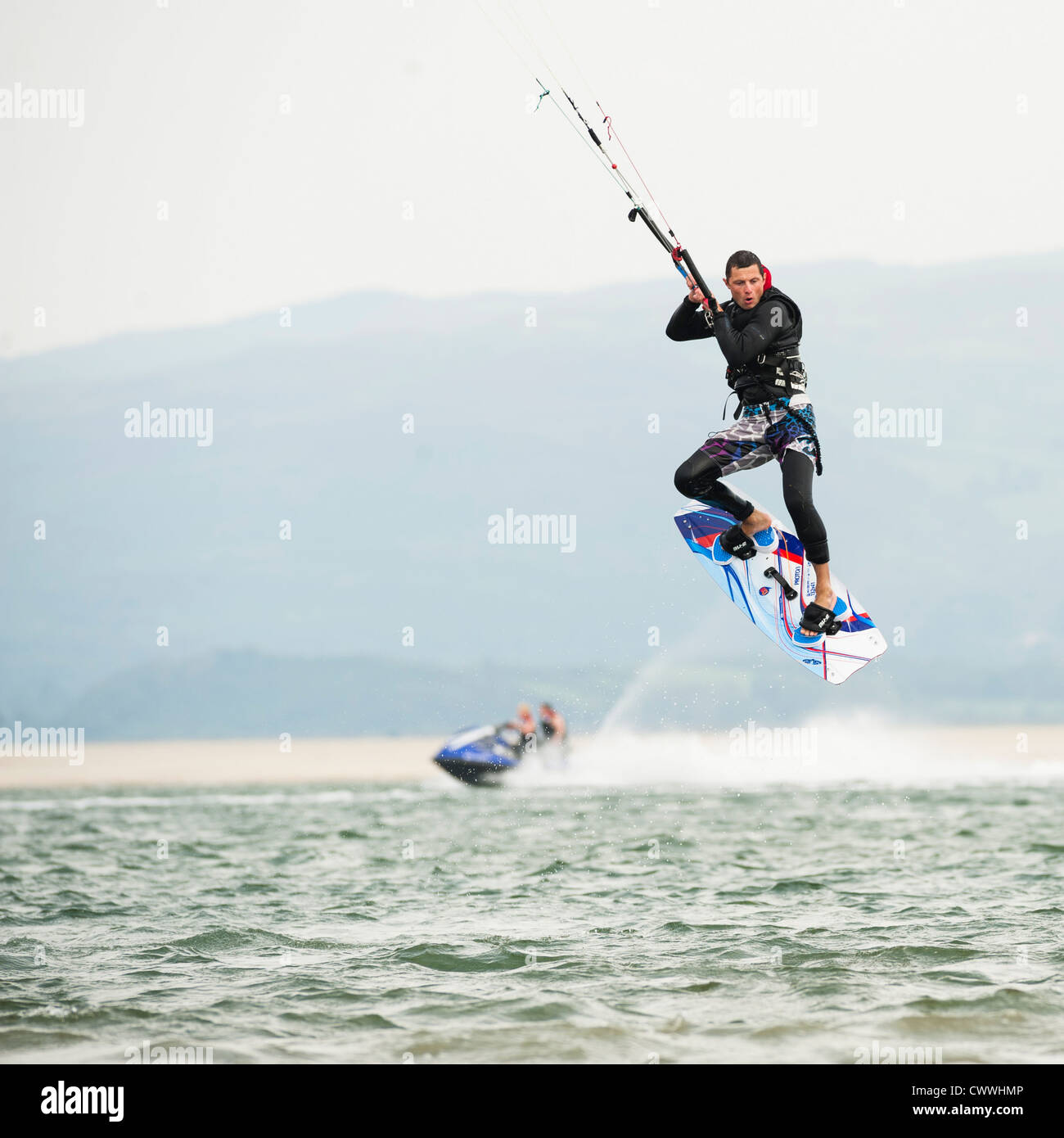 Gli sport acquatici estremi: un uomo kite surfing sull'acqua in un pomeriggio di agosto, Ynys las beach, Dyfi estuary, West Wales UK Foto Stock