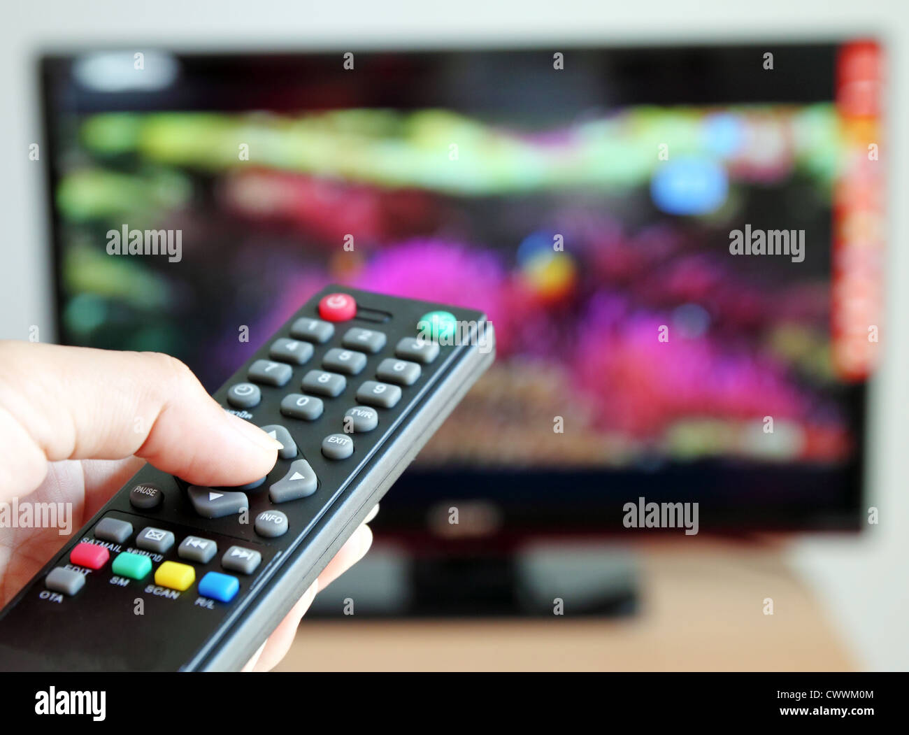 Mano puntando il telecomando verso il televisore Foto Stock