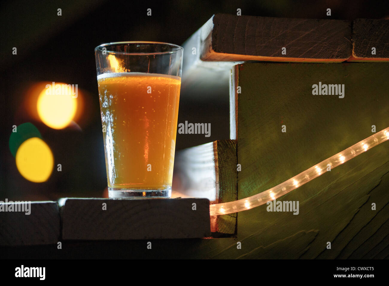 Illuminata di una pinta di birra in appoggio su un gradino in legno con illuminazione a fune Foto Stock