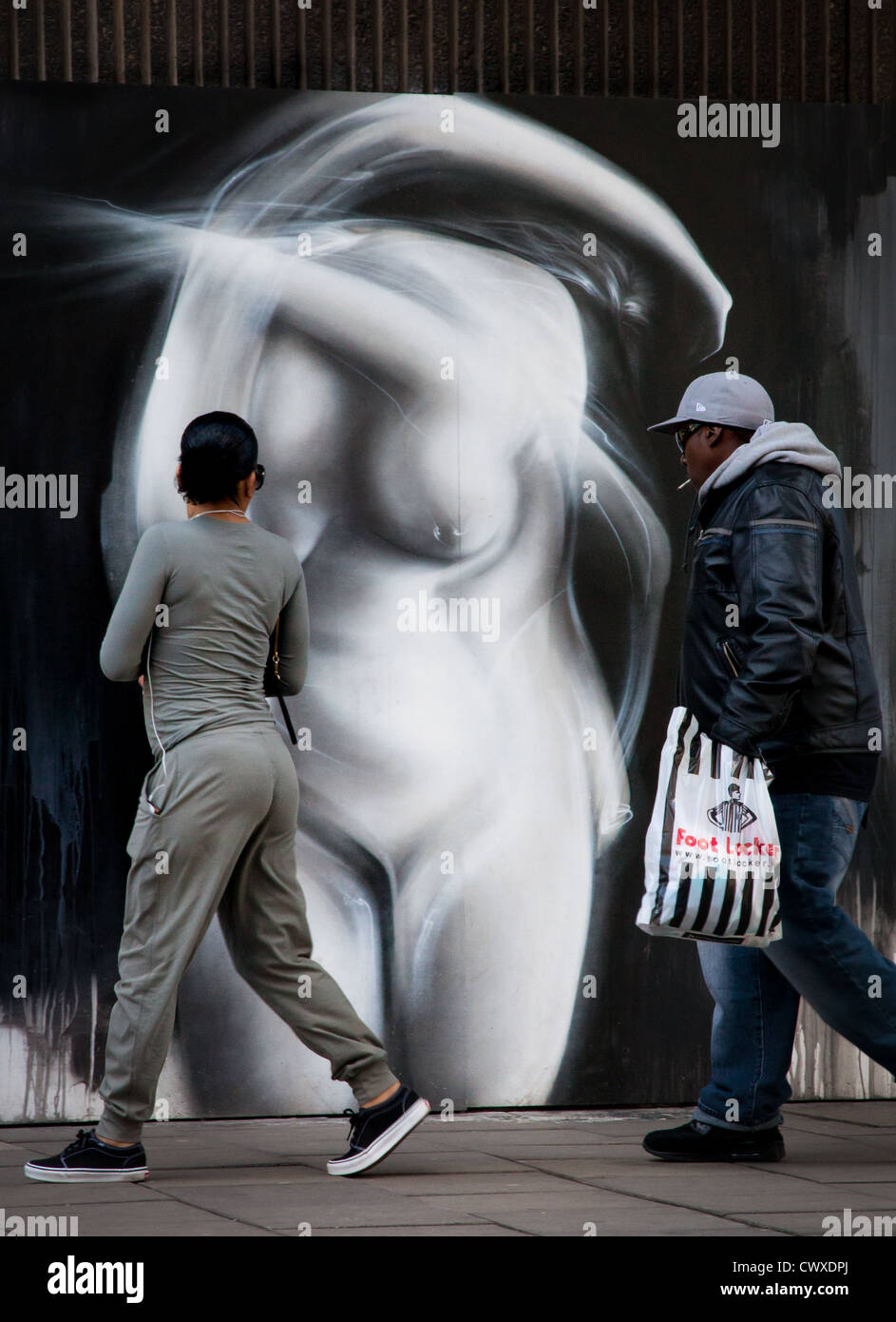 La gente camminare passato graffiti Foto Stock