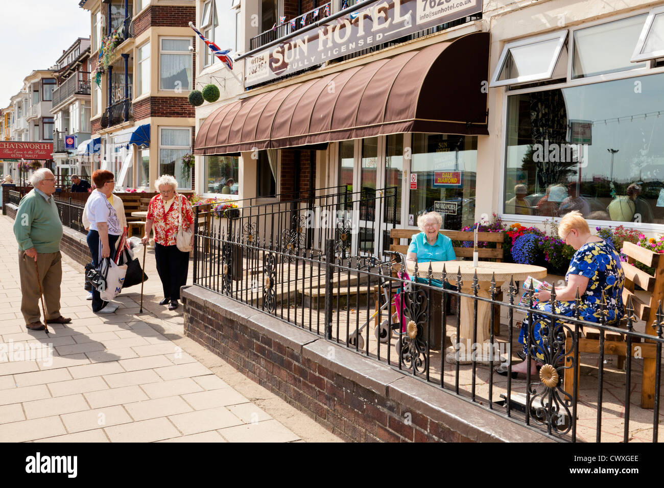 Le persone anziane godendo una giornata di sole in estate presso un hotel fronte mare a Skegness, Lincolnshire, England, Regno Unito Foto Stock