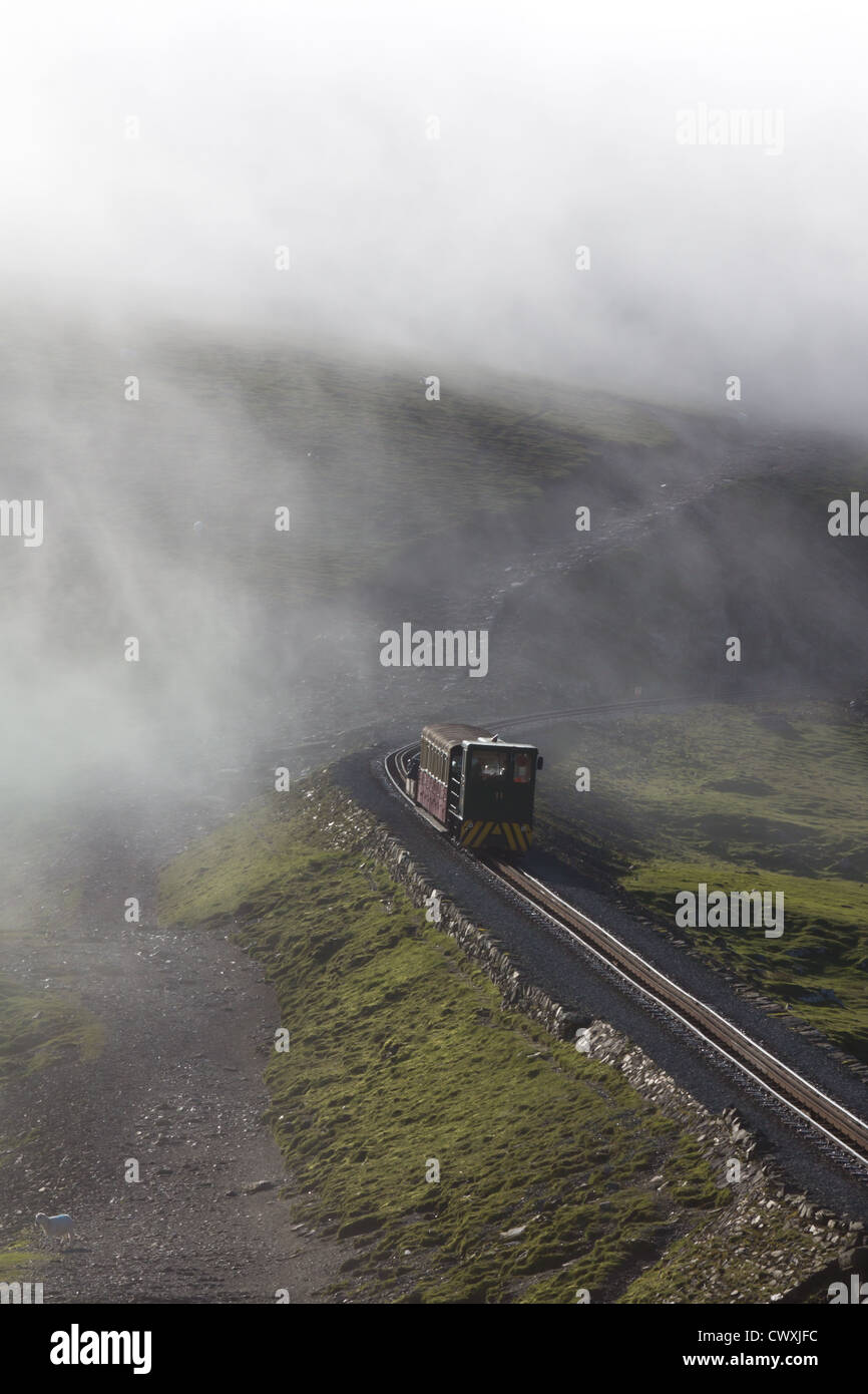 Snowdon Mountain treno ferroviario rende la sua strada verso il basso dalla vetta avvolta dalla nube bassa Foto Stock