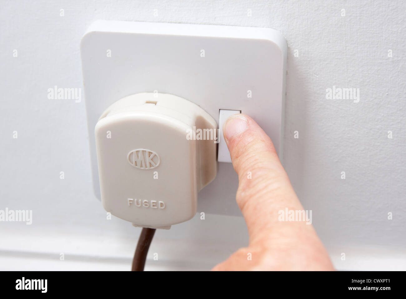 Mettere mano nella spina a 3 contatti della presa elettrica Foto Stock