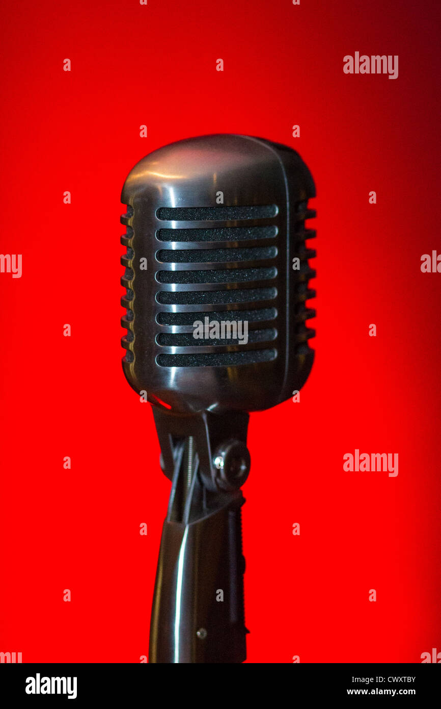 Vecchio stile microfono vocale a un jazz performance, isolata su uno sfondo di colore rosso. Foto Stock