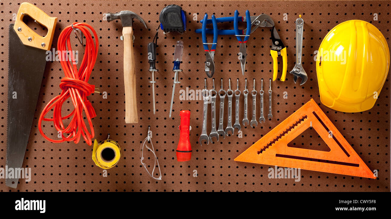 Un tabellone con vari strumenti quali: martello, sega, chiavi, torcia, cavo di prolunga, cacciaviti Foto Stock