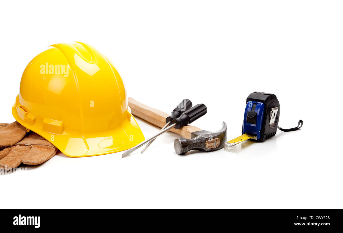 Un casco giallo, pelle guanti da lavoro e vari strumenti di costruzione su sfondo bianco Foto Stock