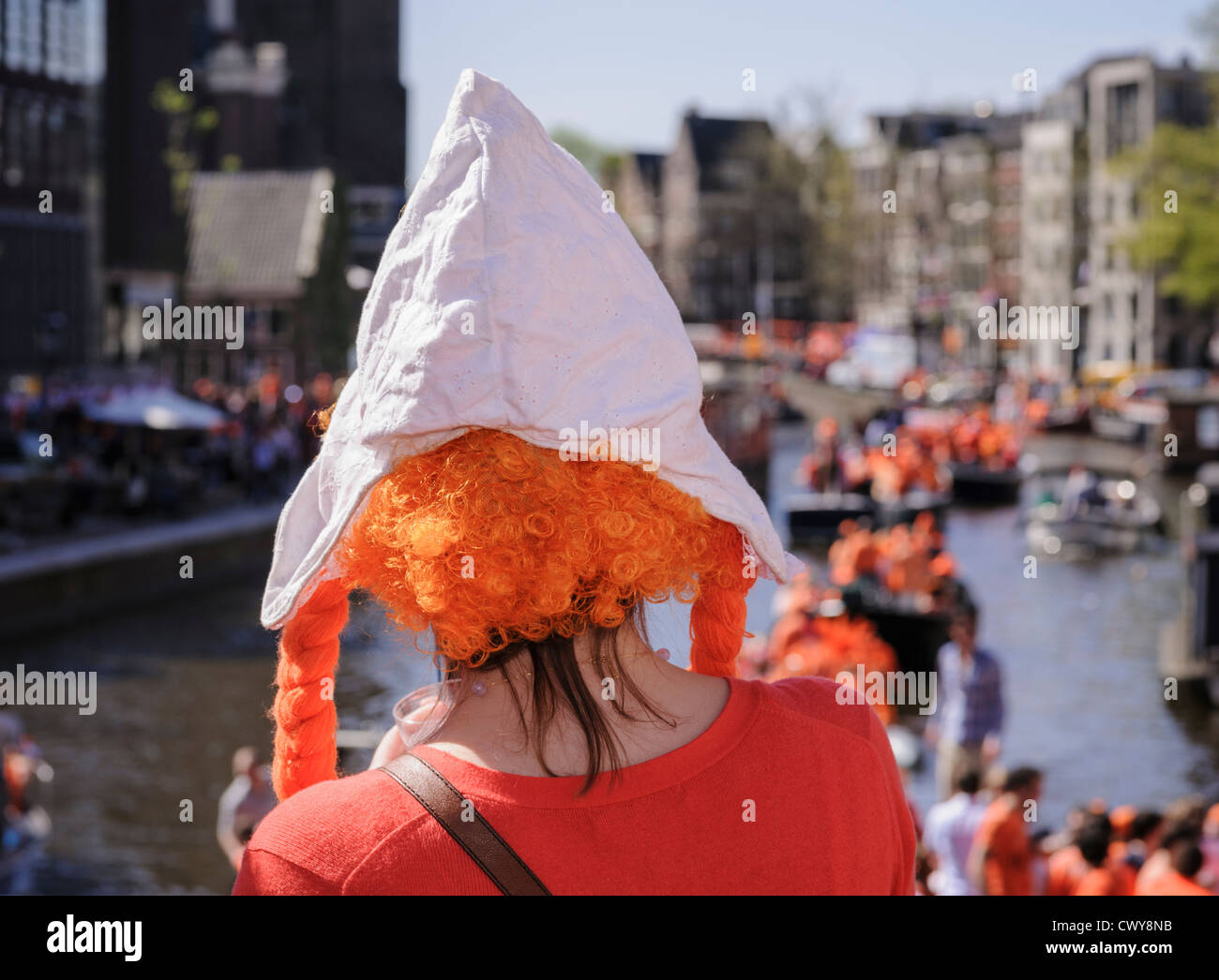 Giovane donna con parrucca arancione e tradizionali olandesi hat su Koninginnedag, o la Festa della Regina, Amsterdam, Paesi Bassi Foto Stock