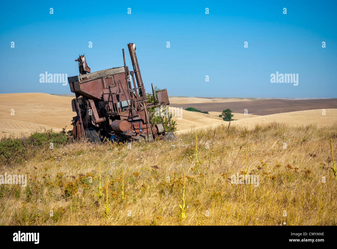 Rusty vecchia mietitrebbia in campi di grano dello stato di Washington Foto Stock