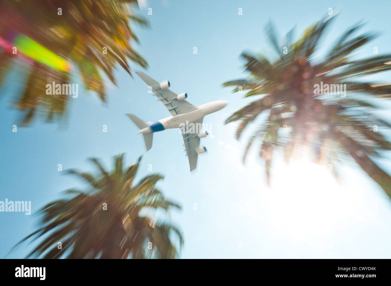 Moderni jet bianco aereo nel cielo sopra di palme al resort tropicale. Sun con lens flare. Foto Stock