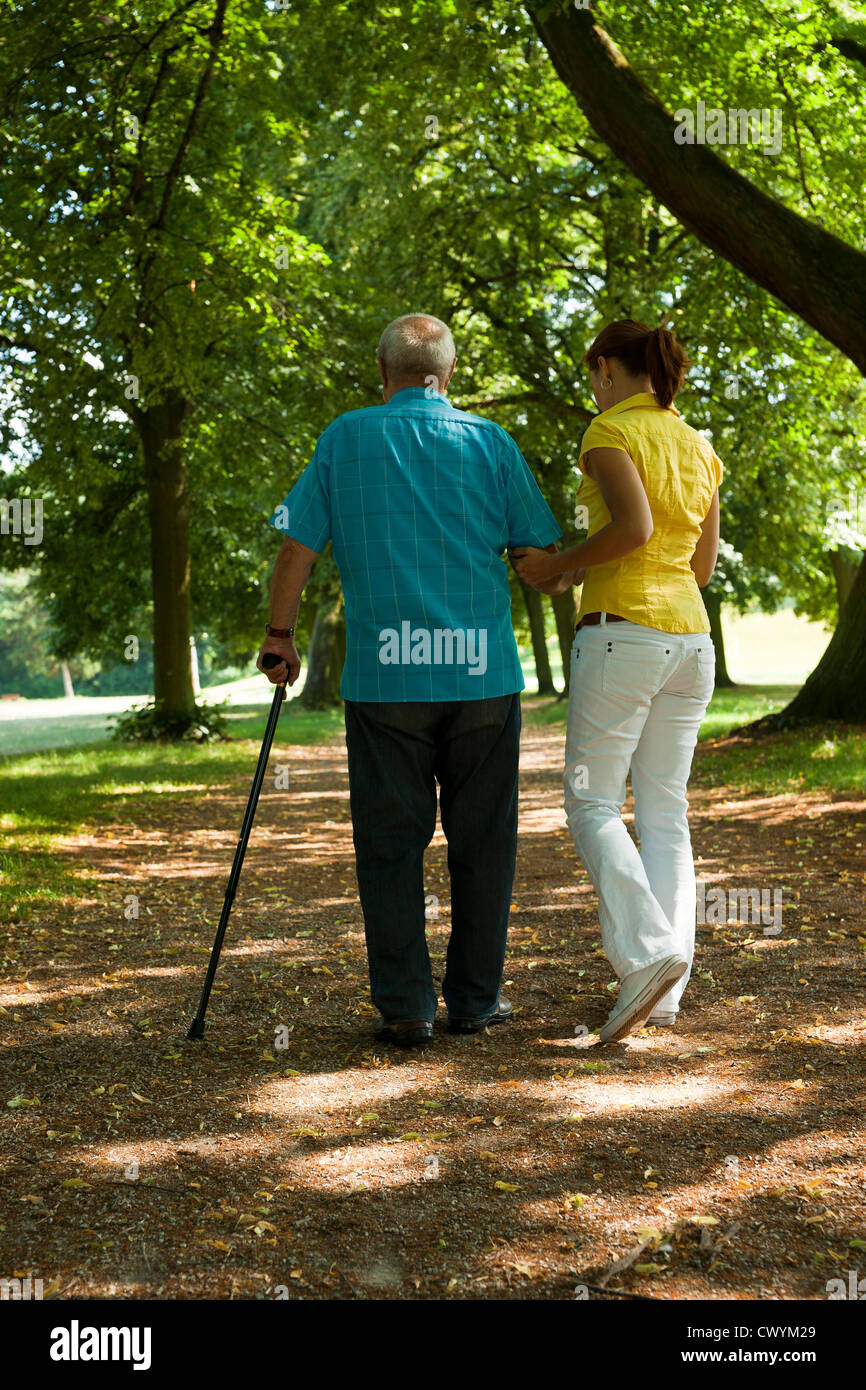 Donna che cammina con l uomo vecchio in posizione di parcheggio Foto Stock