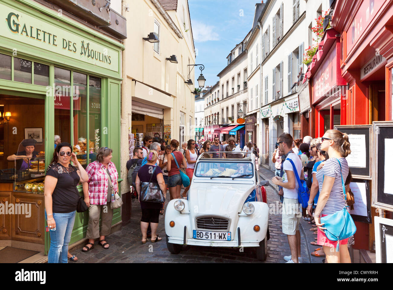 La gente cammina in una affollata strada trafficata in Montmartre con una Citroen 2CV passato guida Parigi Francia EU Europe Foto Stock