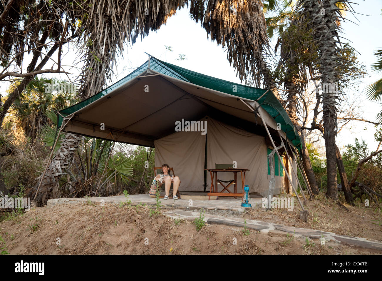 Un turista sulla veranda della sua tenda, Lago Manze tented safari camp, Selous Tanzania Africa Foto Stock