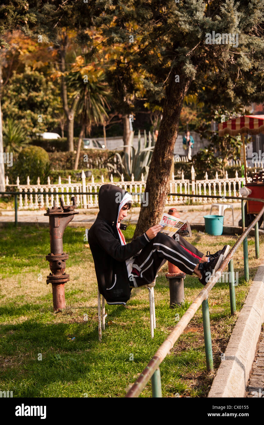 Un giovane uomo di lettura al di fuori delle porte di accesso al palazzo Topkapi a Istanbul Foto Stock