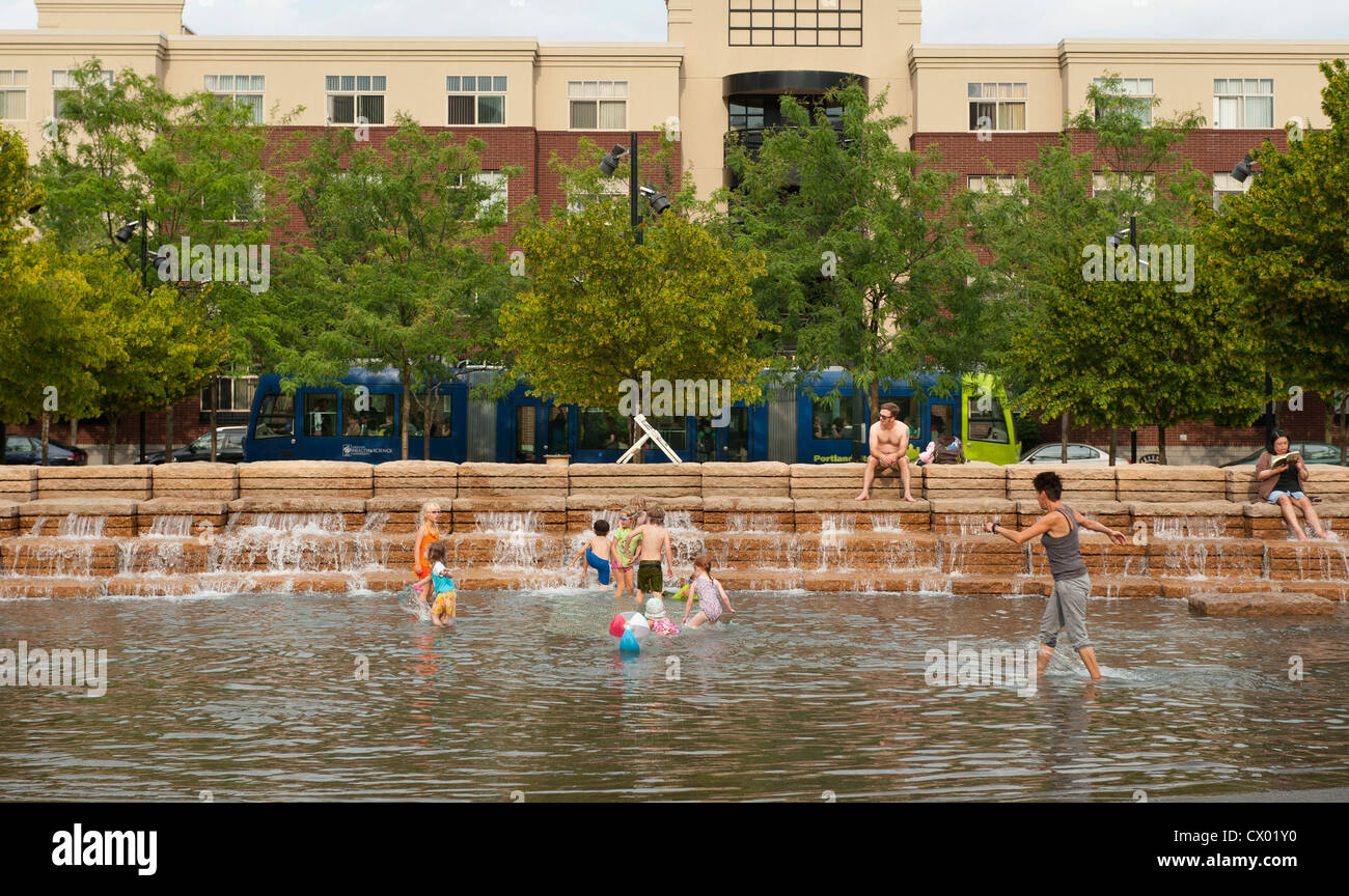 Abitanti delle città rinfrescarvi nel parco urbano fontana e piscina come un tram che va da Foto Stock