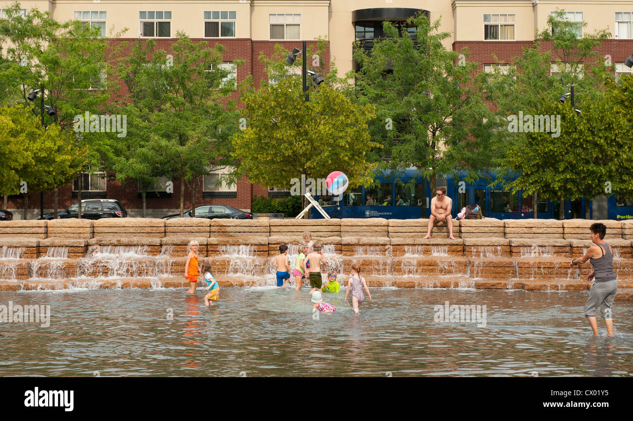 Abitanti delle città rinfrescarvi nel parco urbano fontana e piscina come un tram che va da Foto Stock