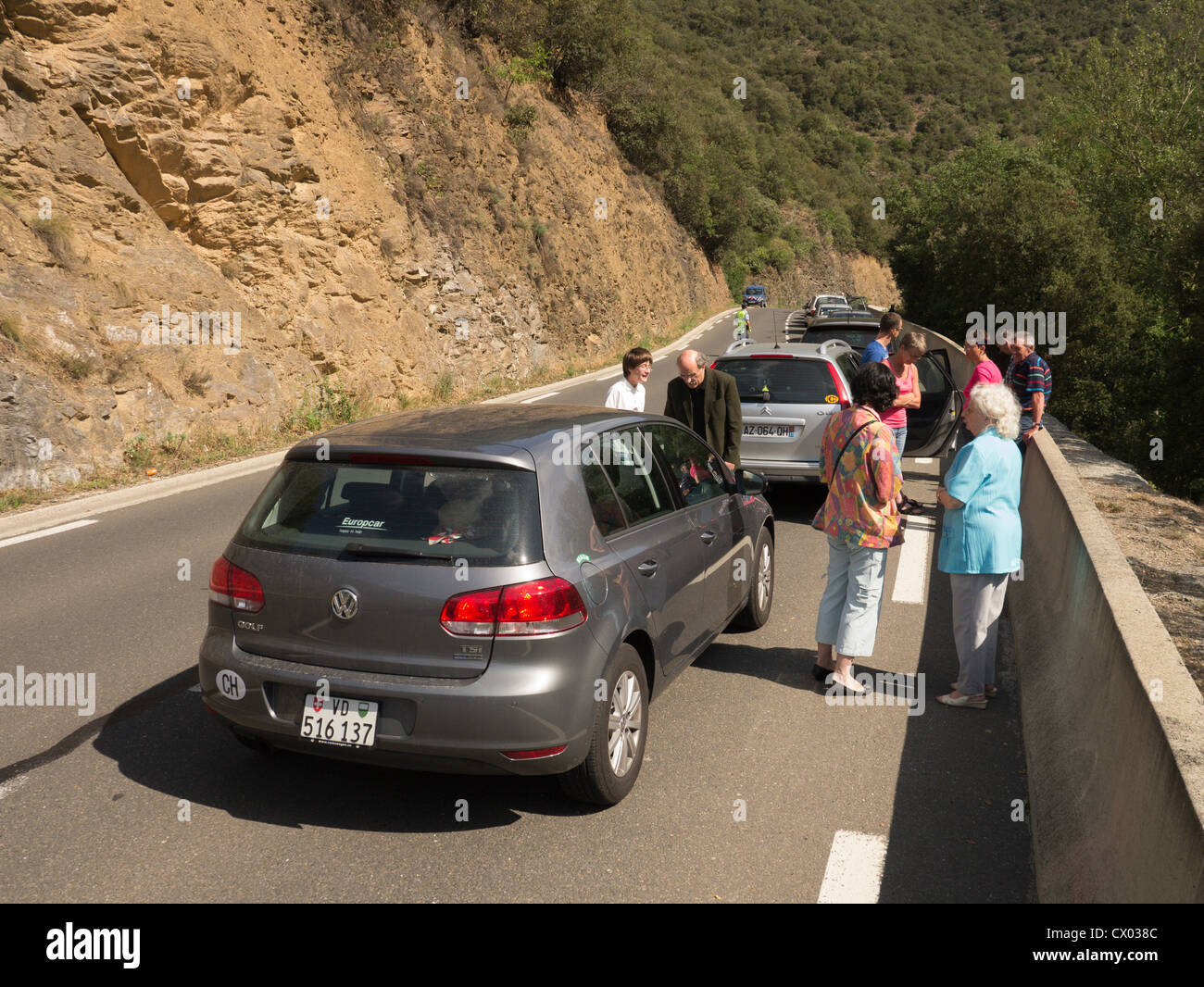 I conducenti e i passeggeri passano il tempo come una strada di montagna è temporaneamente chiusa al traffico Foto Stock